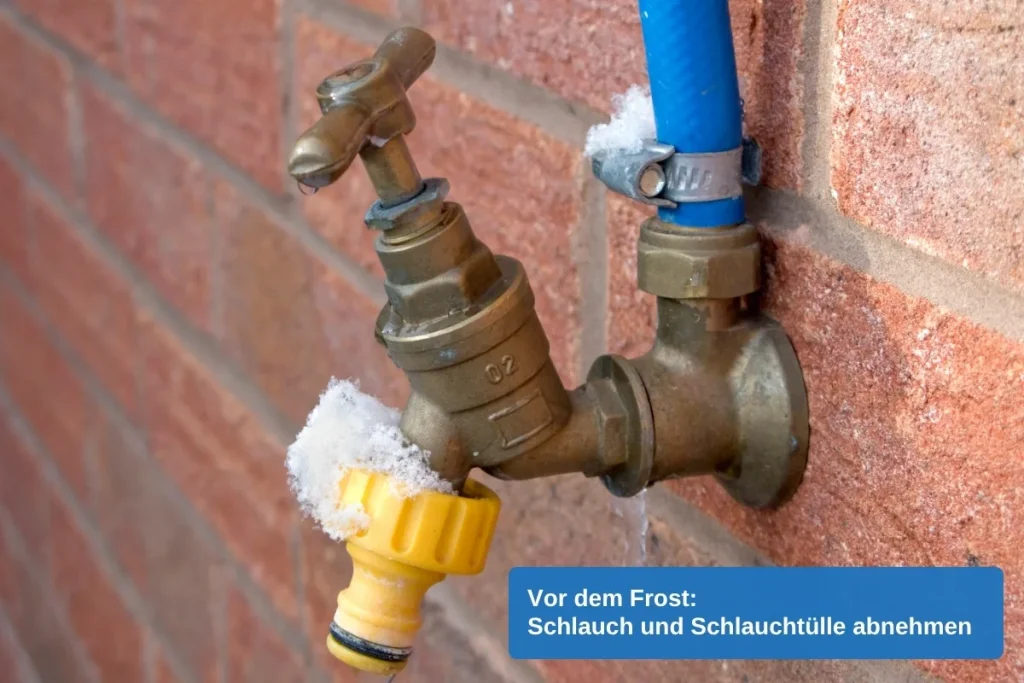 Außenwasserhahn aus Messing an einer Backsteinwand mit angeschlossenem blauem Schlauch und gelber Schlauchtülle, mit Frost überzogen
